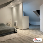 Chambre lumineuse aménagée sous les combles avec parquet clair et murs blancs par Artiseo en Essonne