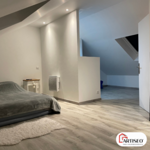Chambre lumineuse aménagée sous les combles avec parquet clair et murs blancs par Artiseo en Essonne